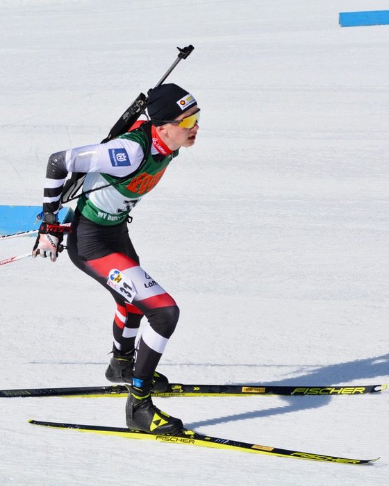Biathlet in der Loipe mit Gewehr am Rücken